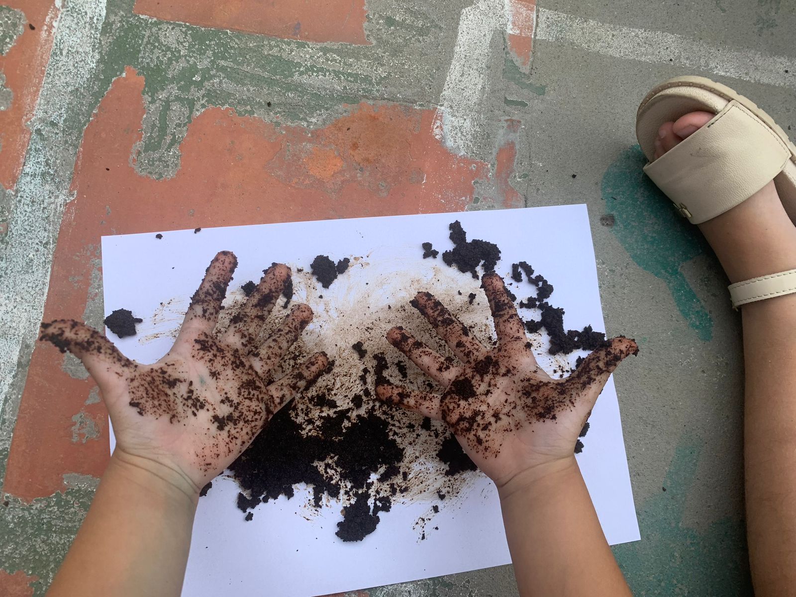 Mãos de criança explorando terra em uma proposta pedagógica